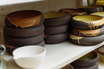 Interesting handmade ceramic plates on the shelf of the Potter's workshop