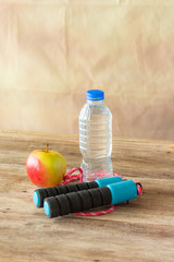 red apple and bottle water with jump robe on wooden colour background,
