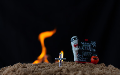 Cross in sad on blurred label Halloween and fire background,