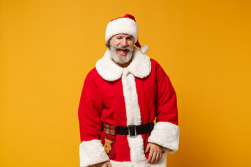 Fototapeta na wymiar Cheerful elderly gray-haired mustache bearded Santa man in Christmas hat posing isolated on yellow background in studio. Happy New Year 2020 celebration holiday concept. Mock up copy space. Blinking.