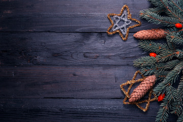 Composition on a black background from old boards with place for text. For the holiday of Christmas and New Year. Fir branches with cones. Top view