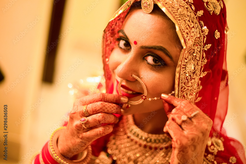 Wall mural Beautiful female model in traditional indian bridal costume with heavy makeup and gold jewelery, indian bride portrait head shot