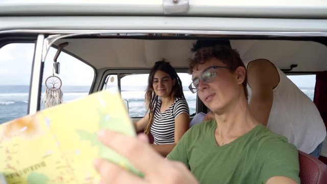portrait of young people inside car using a map on a road trip for directions