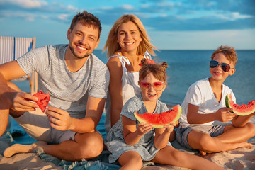 Portrait of happy family eating watermelon on sea beach