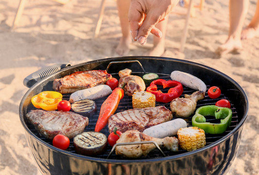 Man cooking tasty food on barbecue grill outdoors, closeup