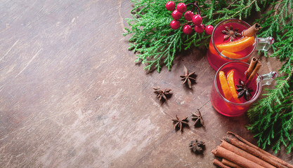 Winter christmas drink.glasses of mulled wine with cinnamon, anise and fir tree branches with decorations on wooden background with copy space. top view.