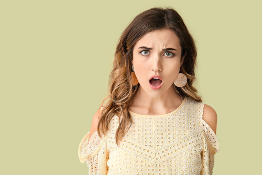 Surprised young woman on color background