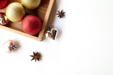 Holidays new year concept. Christmas balls on wooden tray with festive decoration on  white background. Copy space flat lay top view.