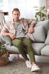 Portrait of handsome young man sitting on sofa at home