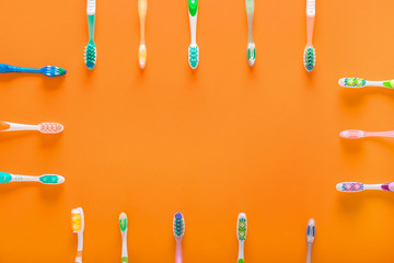 Frame made of tooth brushes on color background