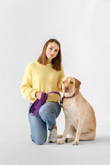 Beautiful young woman with cute dog on light background