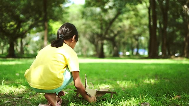 girl kid playing as pilot by running and holding paper plane in park , funny dream concept