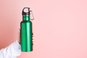 Female hand with sports water bottle on color background