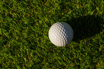 Golf ball on the green,Green grass with golf ball close-up in soft focus at sunlight. Sport playground for golf club concept - wide landscape as background for your lettering about golf playing.