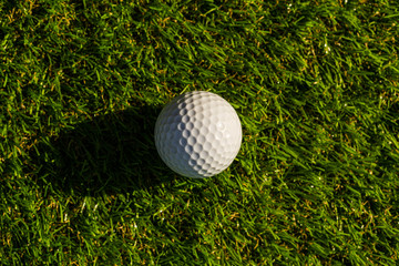 Golf ball on the green,Green grass with golf ball close-up in soft focus at sunlight. Sport playground for golf club concept - wide landscape as background for your lettering about golf playing.
