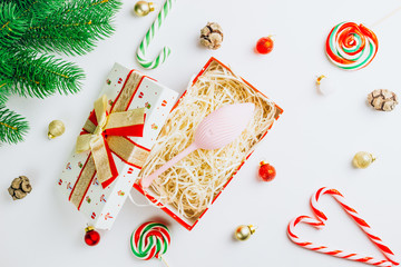 Christmas or New Year composition. Pink vibrator in a gift box on white background. Image for the festive season, for sales in sex shops. Top view. Copy space. Flat lay. Christmas minimal concept.