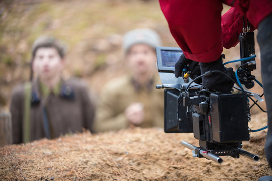 A man with camera in hand is filming the actors