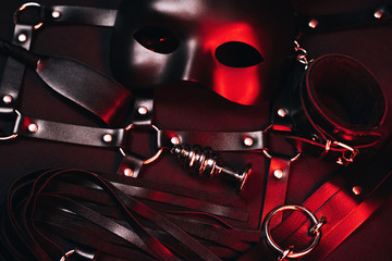 Female set of sex toys from a sex shop for BDSM sex. Mask, leather belt, choker, handcuffs, whip and anal plug