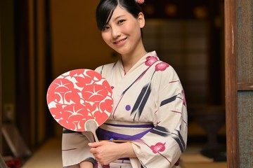 うちわ片手に微笑む浴衣姿の若く美しい女性