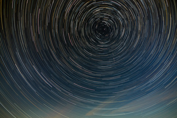 Star trail in the night sky with clouds.