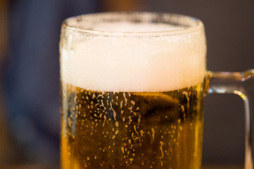 A glass of beer with froth and water drops