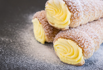Puff pastry horns filled with vanilla cream and powdered sugar