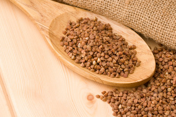 Buckwheat in a wooden spoon. On wood