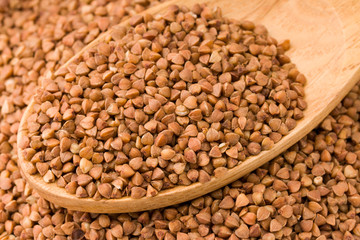 Buckwheat in a wooden spoon. On wood