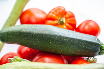fresh vegetables in the foreground, zucchini tomatoes and cucumbers