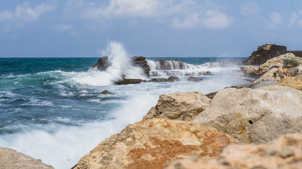Surf on beach with sand and Ceasaria castle bay, Israel