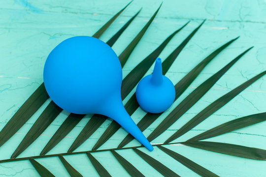 two blue syringes on a background of green twigs