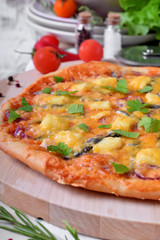 Round pizza with anchovies, mozzarella cheese and tomato sauce garnished with fresh parsley on white table