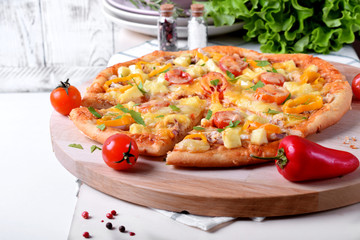 Pizza with chicken, cheese, tomatoes and bell peppers served on the round wooden board. Italian cuisine meal