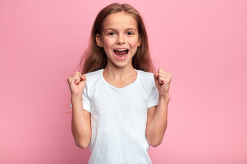 Close-up emotional portrait of attractive cheerful excited girl keeping hands in fists,shouting,...