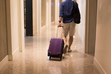 Fototapeta na wymiar Man pulling suitcase and entering hotel