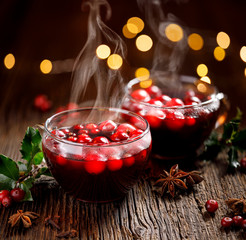Christmas cranberry mulled red wine with aromatic cinnamon, anise and cloves in glass cups on a wooden table. Christmas hot drink