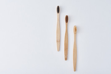 three wooden bamboo toothbrushes on a white background, top view.  Dental care concept