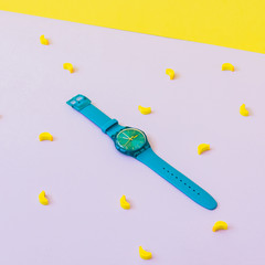 Fashionable blue watches among mini rubber bananas. minimalism