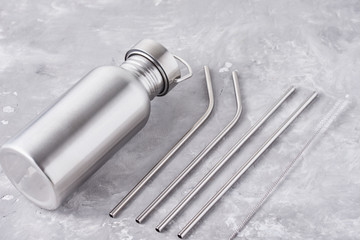Reusable plastic free items on a gray background. Top view of aluminun bottle and metal tubes. Zero...