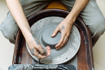 Girl pours water on clay on a Potter's wheel. Creating a ceramic vase