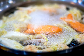 The boiling food in the pot consists of vegetables and meats that are hot and pleasant to the body