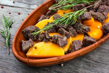 Sliced pumpkin baked with meat in a clay pot. Autumn meal with rosemary and spices