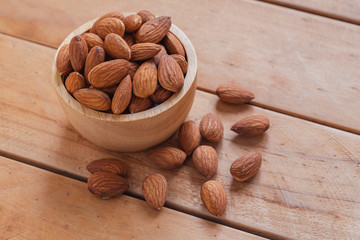 Almonds in wood bowl on wooden table background