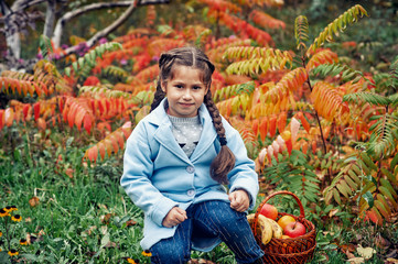 little girl model in coat on autumn walk . child holding apples