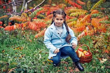 little girl model in coat on autumn walk . child holding apples