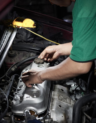 Dress valve cover. Technician service close the cover part. Auto mechanic working in garage.