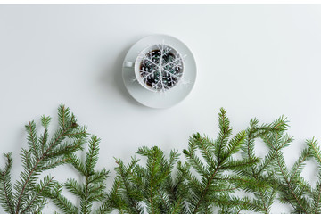 Fototapeta na wymiar cup of black coffee and glowing snowflake in spruce branches on a white table. Christmas and New Year concept. Coffee art. Flat lay, top view.