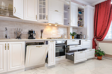 Luxury modern white kitchen interior with open doors and drawers