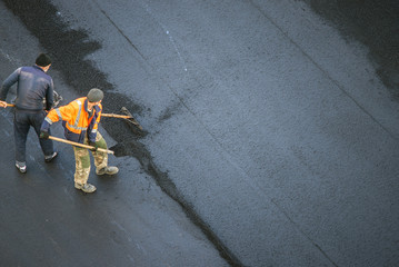 Workers lay a new asphalt coating using hot bitumen. Work of heavy machinery and paver. Top view - obrazy, fototapety, plakaty
