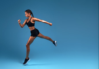 Fototapeta na wymiar flexible strong slim sportswoman running over blue background. lifestyle, free time, spare time, copy space. isolated blue background, studio shot